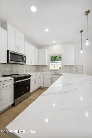 an empty room with wooden floor chandelier fan and windows