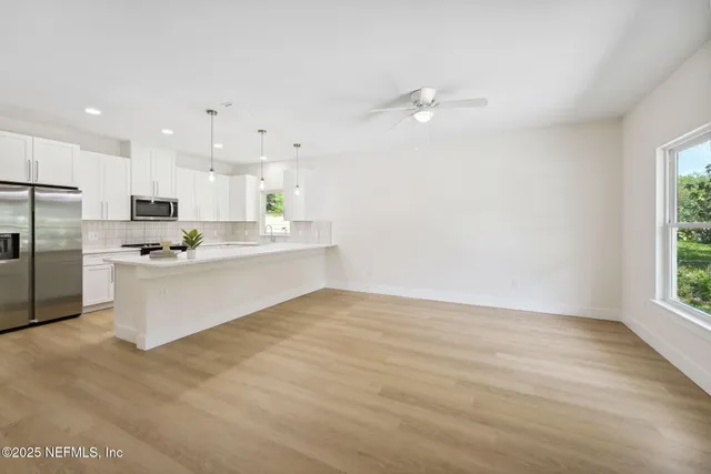 a large white kitchen with kitchen island a sink stainless steel appliances and cabinets