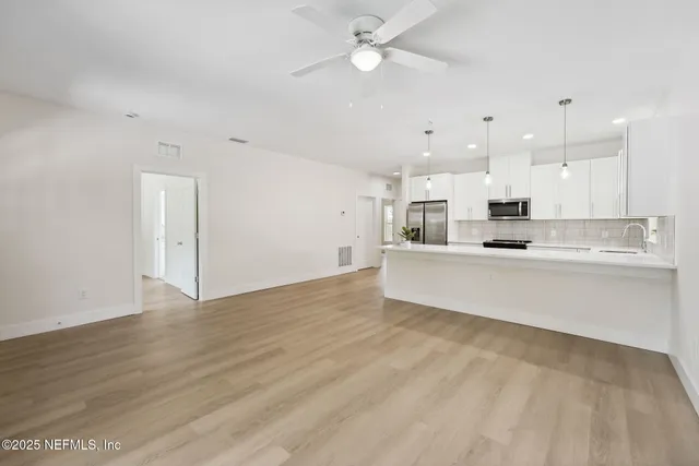 a large white kitchen with kitchen island a sink stainless steel appliances and cabinets