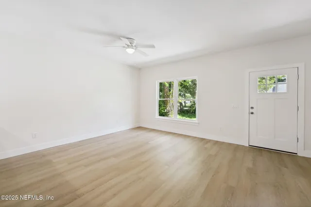 an empty room with wooden floor and windows