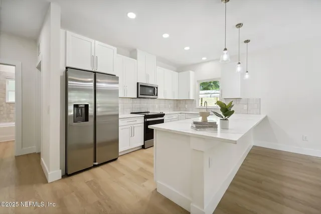 a kitchen with kitchen island a sink stainless steel appliances and cabinets