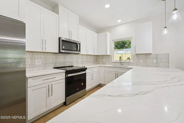 a kitchen with stainless steel appliances white cabinets a sink and a stove