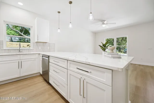 a kitchen with stainless steel appliances granite countertop white cabinets a microwave a window and a sink