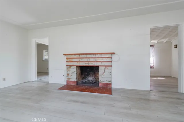 a view of an empty room with wooden floor and a fireplace