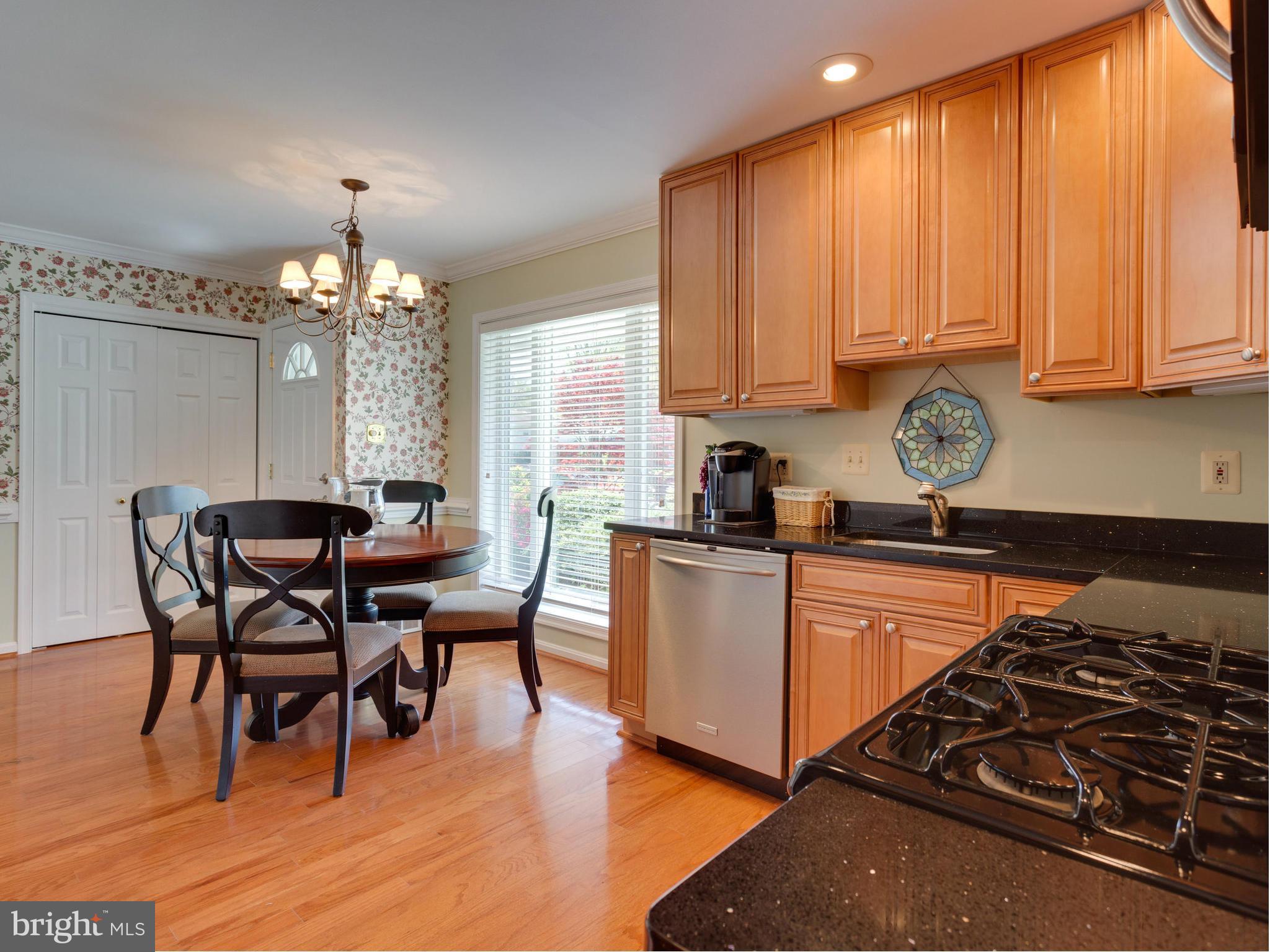 5218 Garner Street Springfield, VA 22151 - Photo 5 of 29 a kitchen with granite countertop a stove a sink dishwasher a dining table and chairs with wooden floor