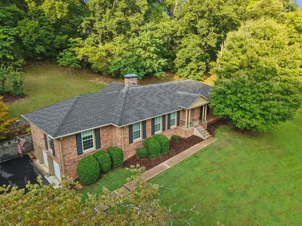 a aerial view of a house next to a yard with plants and large trees