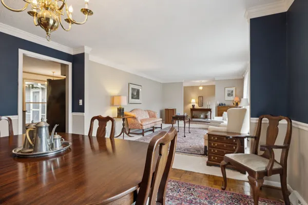 a dining room with wooden floor a chandelier a glass table and chairs