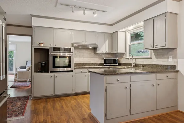 a kitchen with stainless steel appliances granite countertop a stove a sink and a microwave
