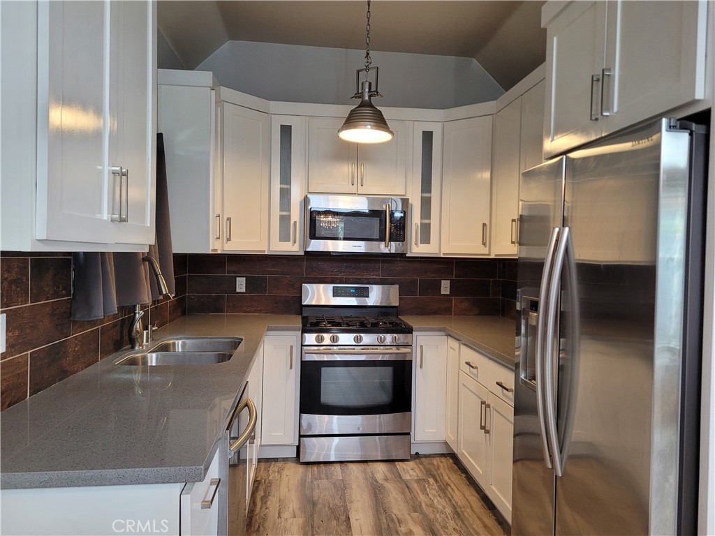 a kitchen with stainless steel appliances granite countertop a sink a stove a refrigerator and a microwave