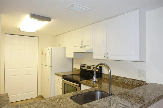 a kitchen with stainless steel appliances granite countertop a sink a refrigerator and a stove