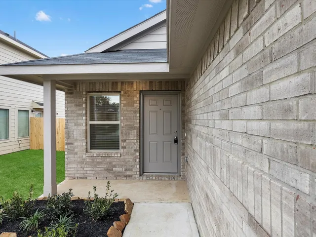 a view of a brick house with a potted plant and floor to ceiling window