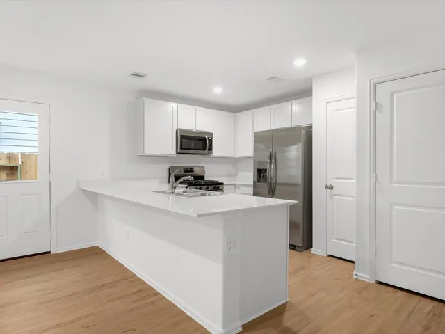 a view of kitchen with microwave refrigerator and cabinets