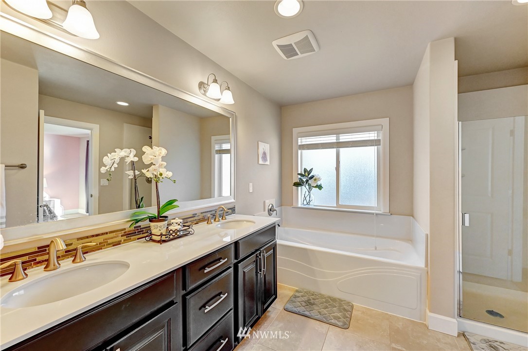 3228 170th Place Southeast Bothell, WA 98012 - Photo 33 of 40 a bathroom with a double vanity sink a large mirror a bathtub and next to a window