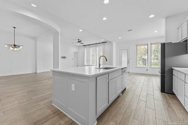 a large white kitchen with a sink and wooden floor
