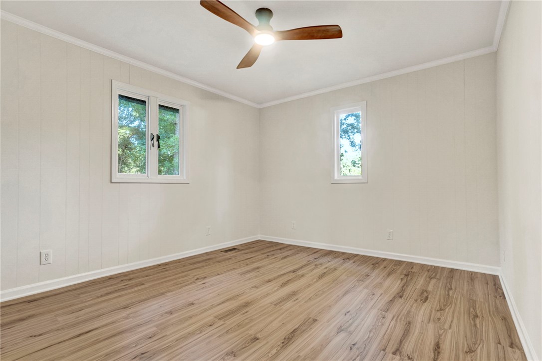 237 Earle Road Central, SC 29630 - Photo 18 of 24 A quiet bedroom with gleaming wood flooring and multiple windows invites peaceful rest.