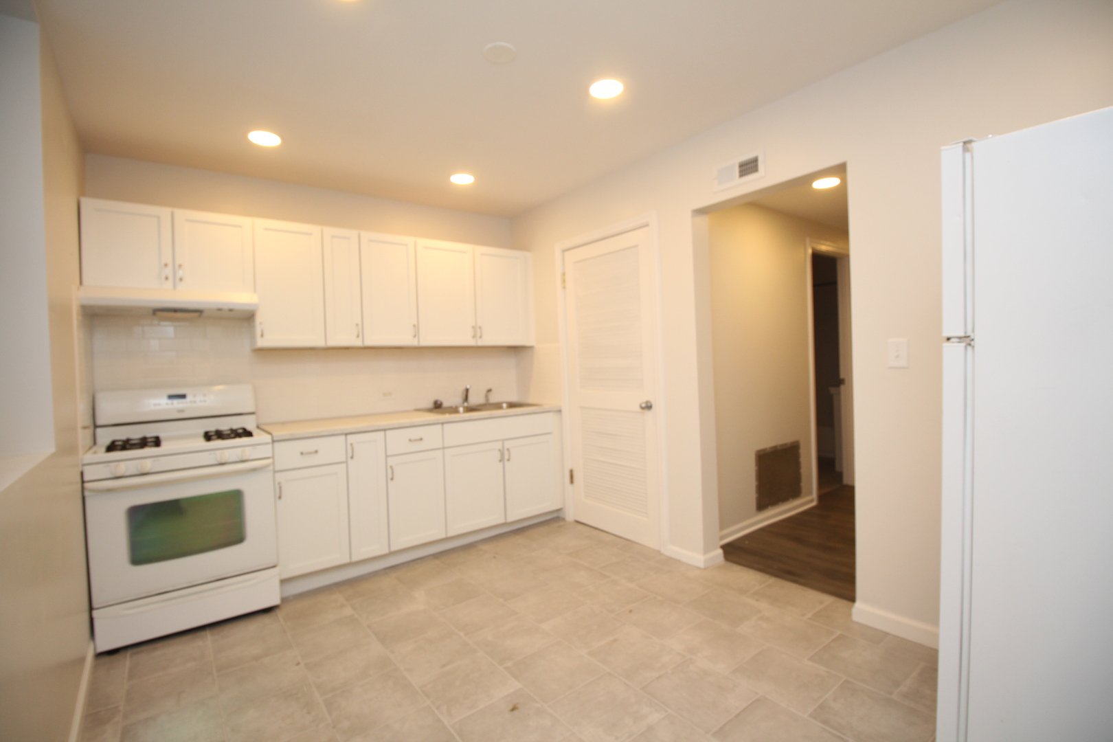120 North Spring Street, Unit 1 Elgin, IL 60120 - Photo 4 of 12 a kitchen with white cabinets and white appliances