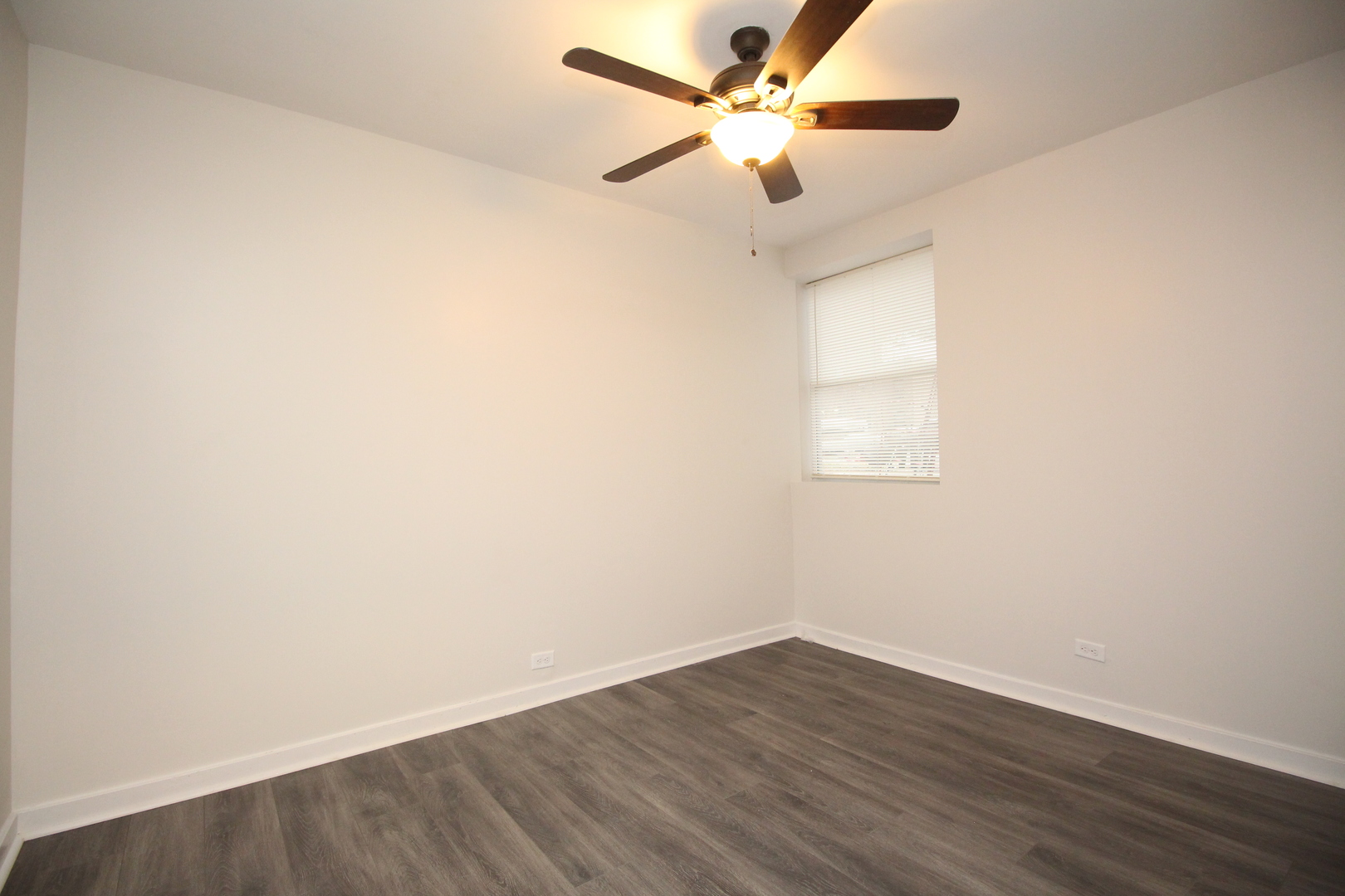 120 North Spring Street, Unit 1 Elgin, IL 60120 - Photo 9 of 12 an empty room with wooden floor and a ceiling fan