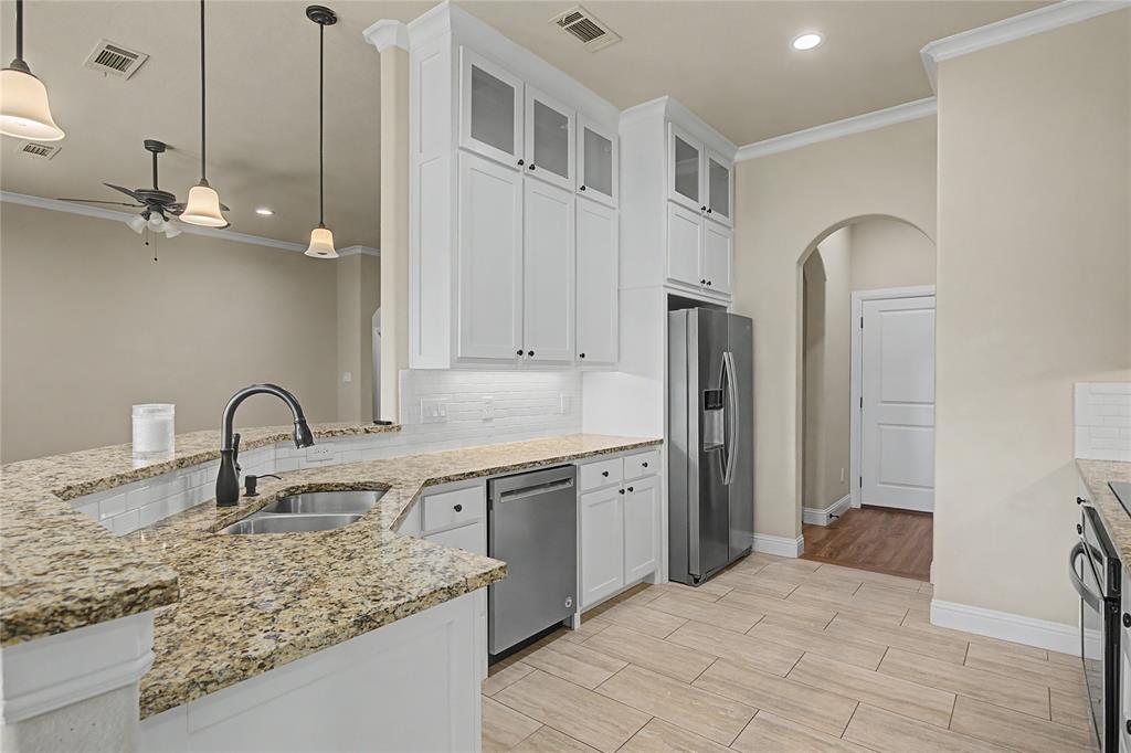 143 Wrigley Drive Springtown, TX 76082 - Photo 15 of 38 Kitchen with white cabinetry, crown molding, light granite counters, and stainless steel dishwasher...upper cabinets to display decor or additional storage