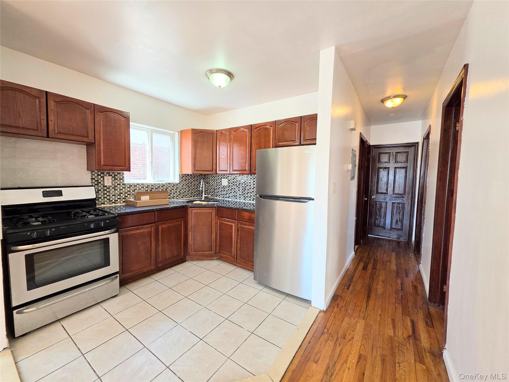 219-23 114th Road Queens, NY 11411 - Photo 4 of 9 a kitchen with a refrigerator a stove top oven and cabinets