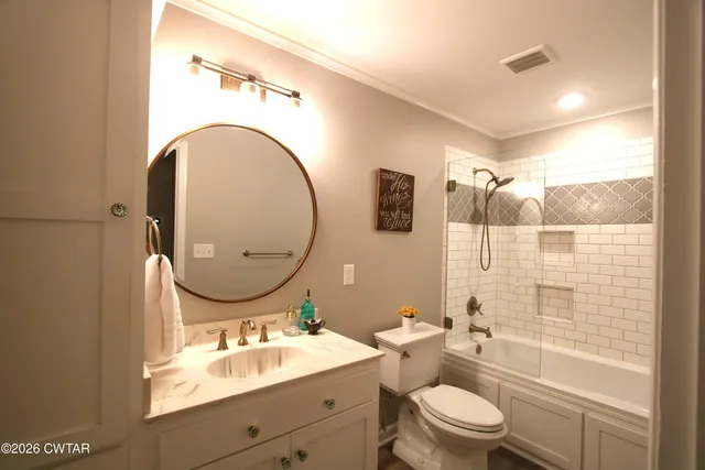 a bathroom with a toilet sink mirror vanity and shower