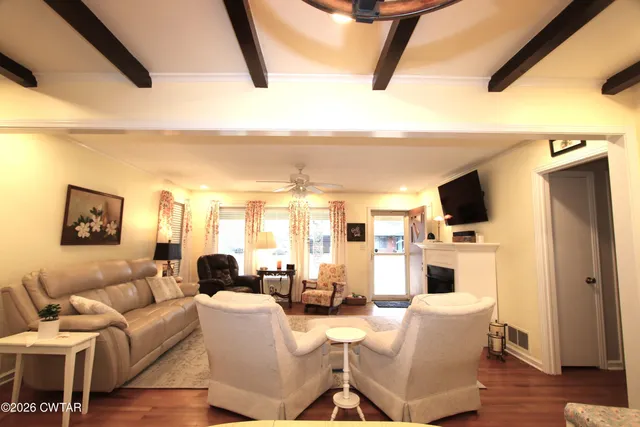 a living room with furniture a flat screen tv and kitchen view