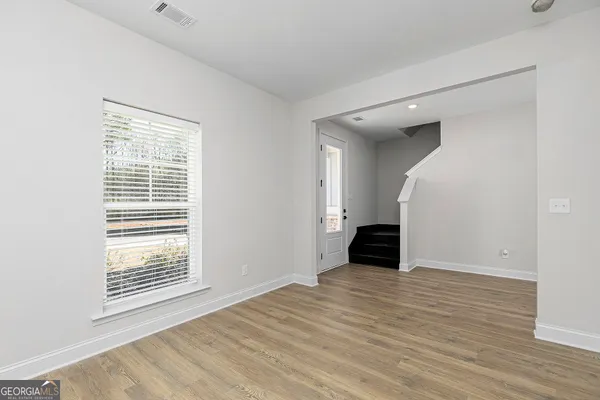 a view of an empty room with wooden floor and a window