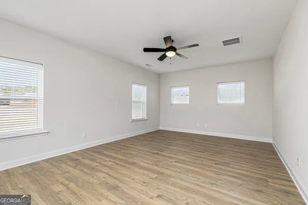 a view of empty room with wooden floor and fan