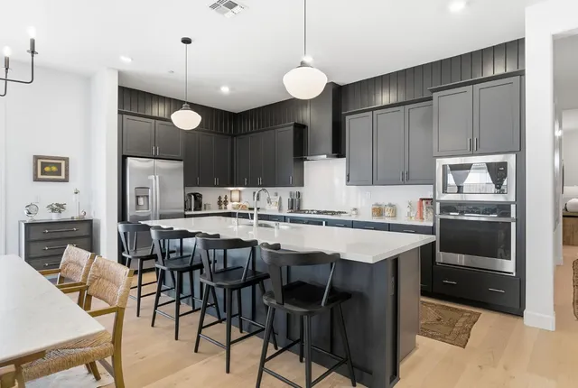 a kitchen with cabinets a sink stainless steel appliances and chairs