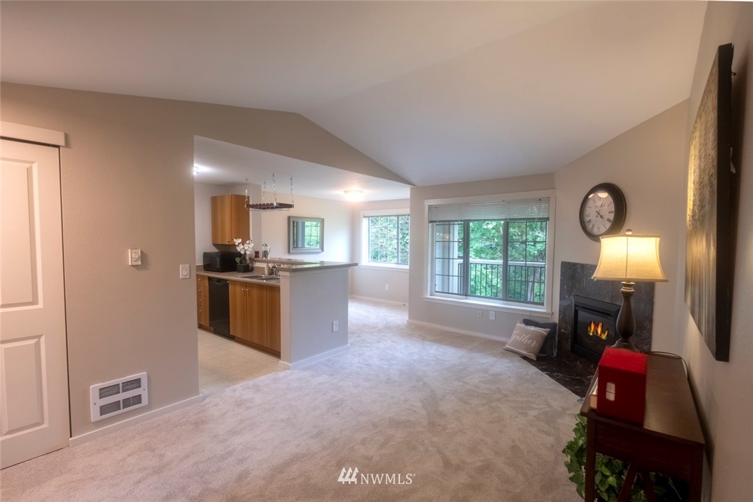 12404 East Gibson Road, Unit F303 Everett, WA 98204 - Photo 10 of 23 a open kitchen with kitchen island granite countertop a refrigerator stove top oven and couches with wooden floor