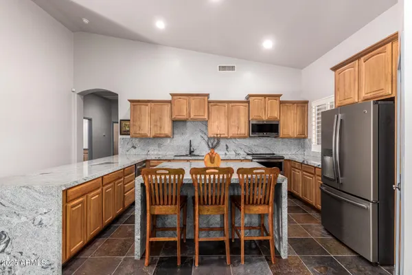 a kitchen with stainless steel appliances granite countertop a refrigerator a sink dishwasher a stove and white cabinets with wooden floor