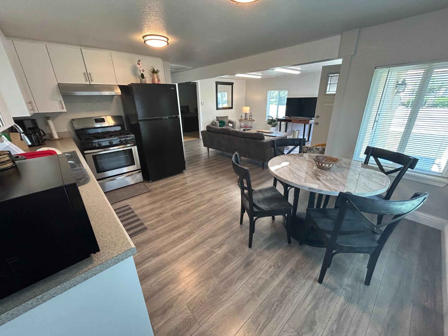 756 1st Street Gilroy, CA 95020 - Photo 8 of 14 a kitchen with stainless steel appliances kitchen island granite countertop a table chairs and a refrigerator