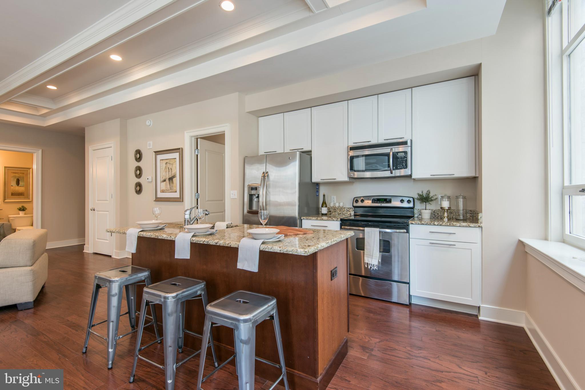 1501 Locust Street, Unit 403 Philadelphia, PA 19102 - Photo 1 of 23 a open dining room with stainless steel appliances kitchen island granite countertop a dining table chairs and a refrigerator