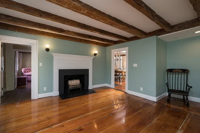 a view of an empty room with wooden floor fireplace and a window