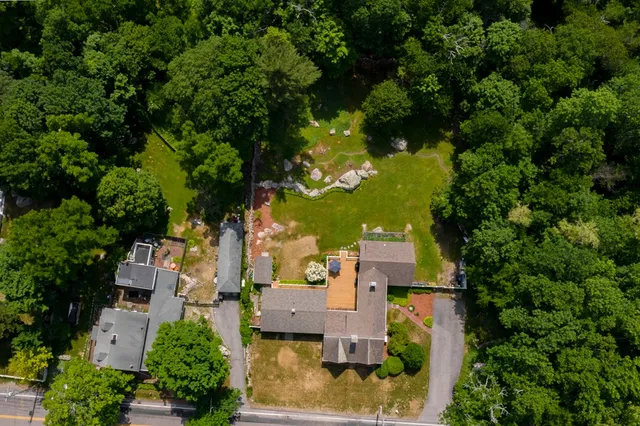 an aerial view of residential houses with outdoor space and trees