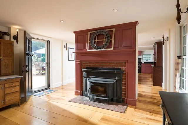 a living room with stainless steel appliances furniture a fireplace and a open kitchen view