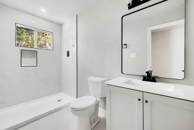 a bathroom with a sink a toilet and shower