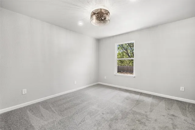 an empty room with windows and chandelier fan