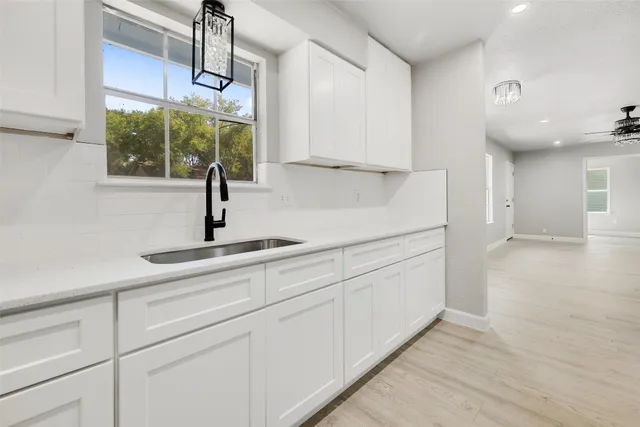 a kitchen with white cabinets and window