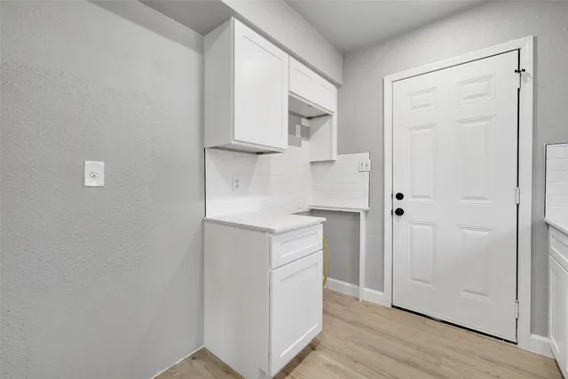 a kitchen with white cabinets and wooden floor