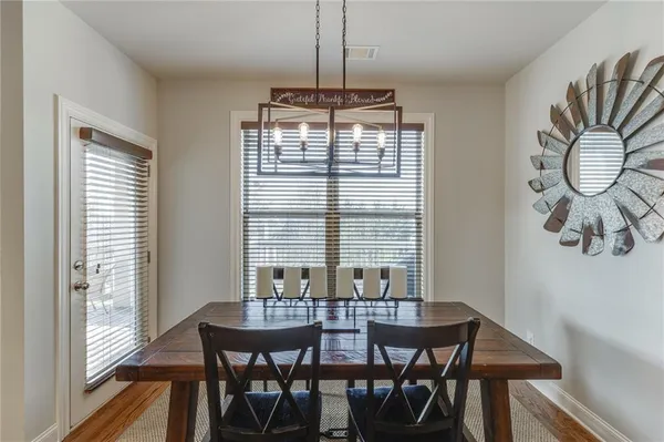 a kitchen with stainless steel appliances a dining table chairs refrigerator and microwave