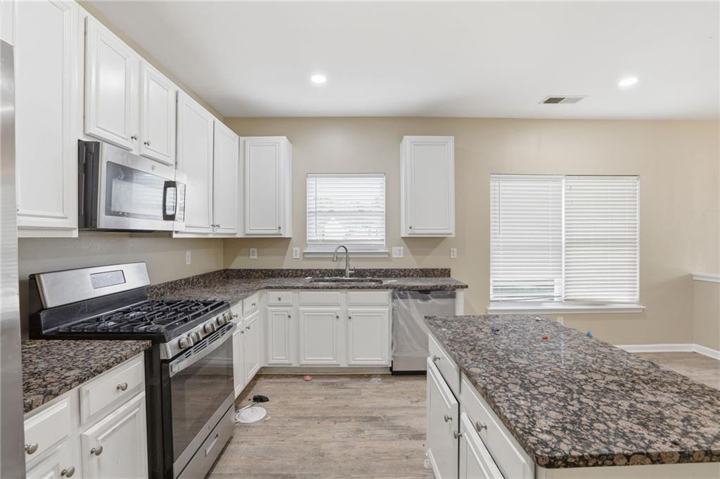 4968 Locherby Drive Fairburn, GA 30213 - Photo 17 of 39 a kitchen with stainless steel appliances granite countertop a stove a sink and a white cabinets