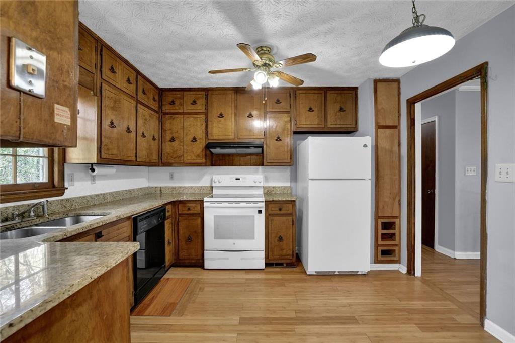 4341 Five Forks Trickum Road Southwest Lilburn, GA 30047 - Photo 5 of 35 a kitchen with stainless steel appliances granite countertop a refrigerator a stove and a sink with wooden floors