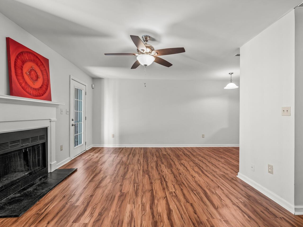 118 Shady Spring Place Durham, NC 27713 - Photo 12 of 33 a view of an empty room with wooden floor a ceiling fan and a fireplace