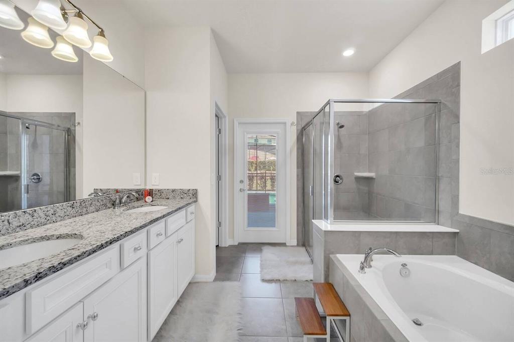 7263 Oakmoss Loop Davenport, FL 33837 - Photo 22 of 57 a bathroom with a granite countertop tub sink shower and mirror