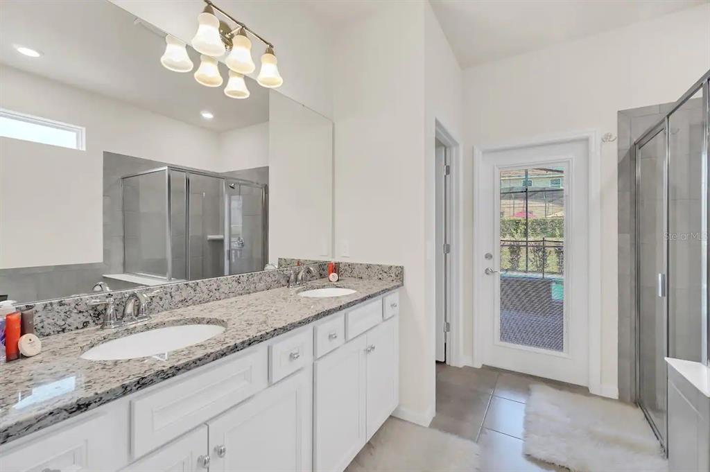 7263 Oakmoss Loop Davenport, FL 33837 - Photo 23 of 57 a bathroom with a granite countertop double vanity sink and a mirror