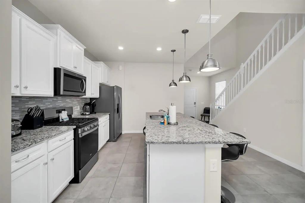7263 Oakmoss Loop Davenport, FL 33837 - Photo 6 of 57 a kitchen with stainless steel appliances granite countertop a sink a stove and a refrigerator
