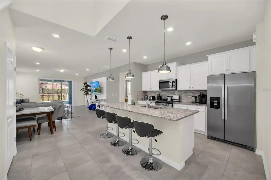 7263 Oakmoss Loop Davenport, FL 33837 - Photo 7 of 57 a large kitchen with kitchen island a sink table and chairs