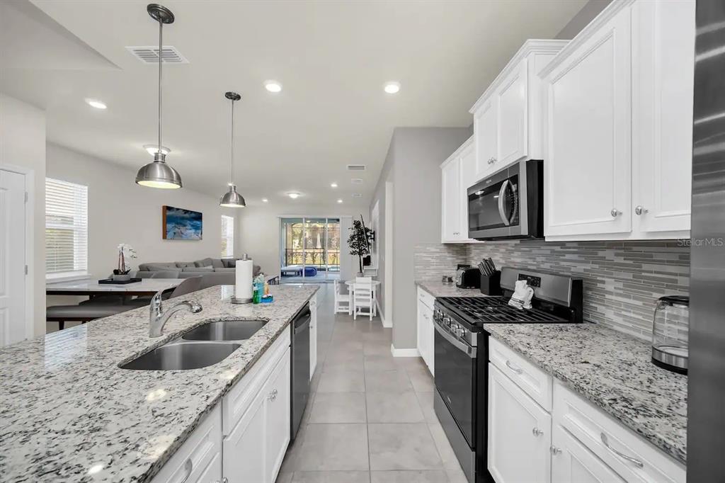 7263 Oakmoss Loop Davenport, FL 33837 - Photo 8 of 57 a kitchen with stainless steel appliances granite countertop a sink a stove and cabinets