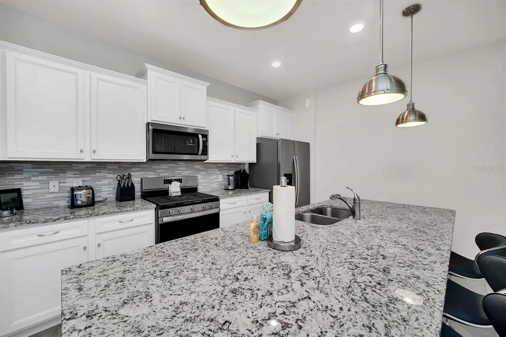 7263 Oakmoss Loop Davenport, FL 33837 - Photo 10 of 57 a kitchen with a stove a sink and a microwave