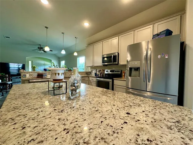 a kitchen with stainless steel appliances kitchen island granite countertop a refrigerator and a stove top oven